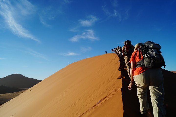 Eine Reisegruppe wandert über die Sanddünen von Sossusvlei in Namibia