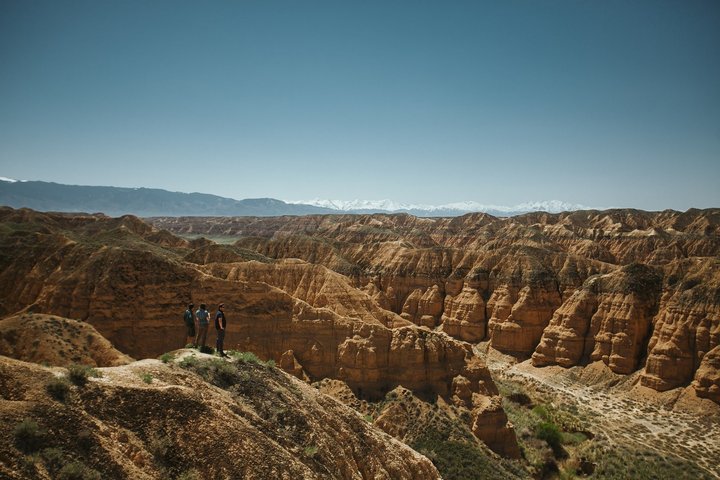 Drei Personen blicken über den Charyn-Canyon mit seinen Felsformationen