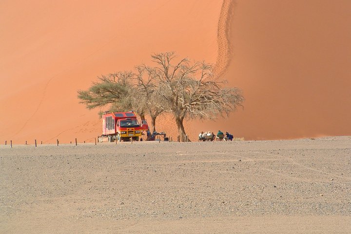 Safarifahrzeug steht vor den Sanddünen von Sossusvlei 