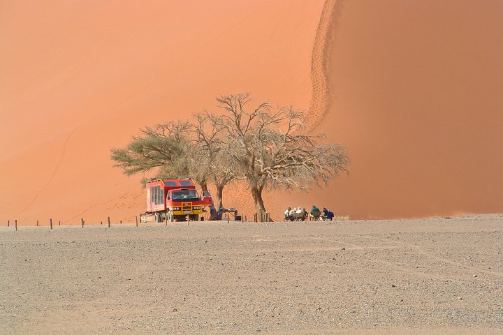 Safarifahrzeug steht vor den Sanddünen von Sossusvlei 