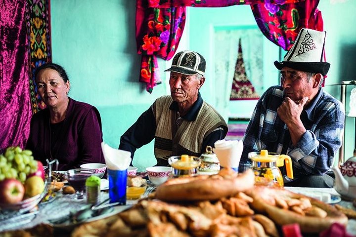 Zwei Kirgisen und eine Kirgisin am reichhaltig gedeckten Tisch