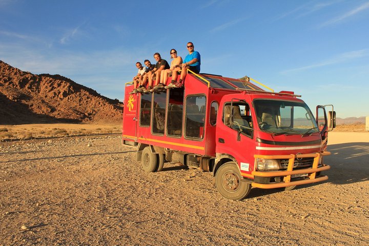 Touristen sitzen auf dem Dach des Safari-Fahrzeugs