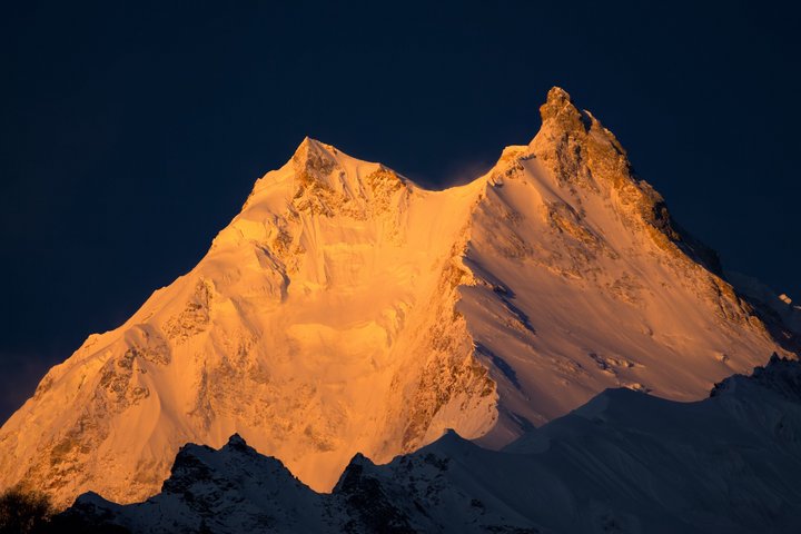 Die ersten Sonnenstrahlen erleuchten den Gipfel des Manaslu in Nepal