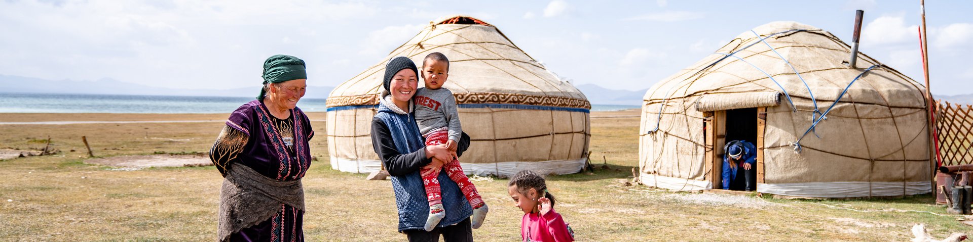 Eine Nomadenfamilie steht vor ihren Jurten am See Son Köl in Kirgistan