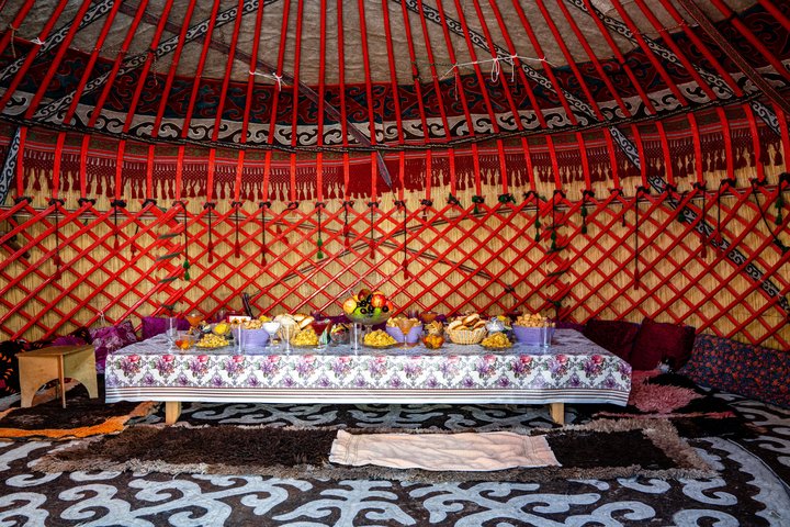 Kirgisische Jurte von Innen mit einem reichhaltig gedeckten Tisch