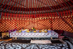 Kirgisische Jurte von Innen mit einem reichhaltig gedeckten Tisch