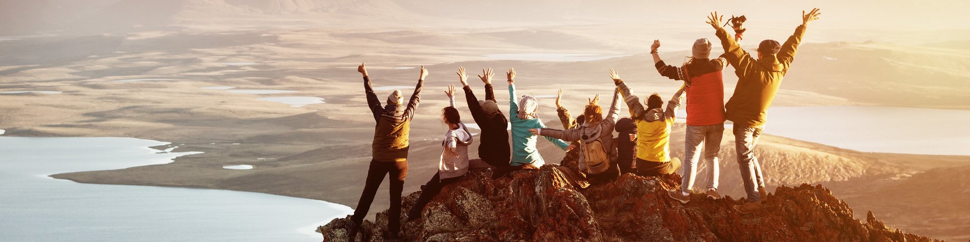 Team - Gruppe von Mitarbeiter:innen auf einem Berggipfel bei Sonnenaufgang