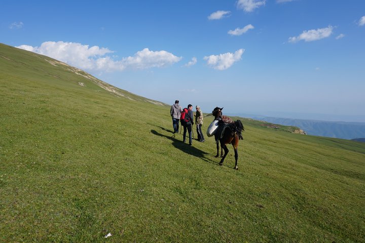 Zwei Wanderer mit Reiseleitung und einem Pferd unterwegs in Aserbaidschan