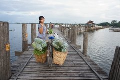 Eine einheimische Frau mit einem Fahrrad auf einem Holzsteg