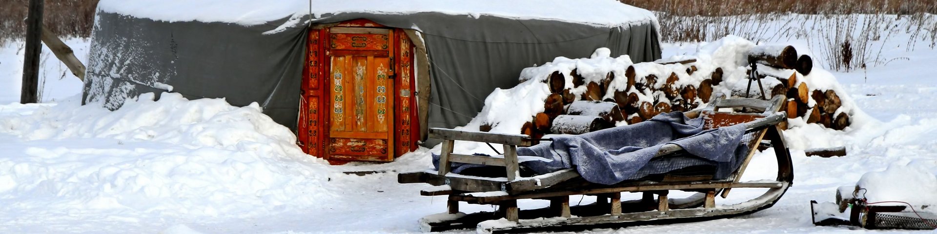 Jurte im Schnee mit Holzschlitten in Kirgistan