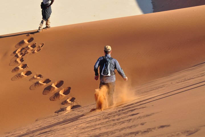 Zwei Touristen rennen durch die Sanddünen in Namibia