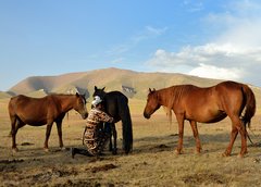 Kirgisische Nomadin melkt ihre Pferde