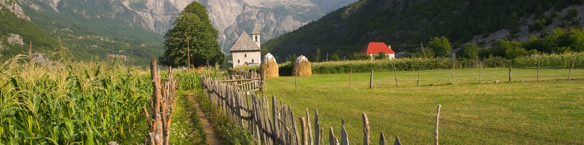 Ein Pfad mit einem Holzzaun führt zur Kirche von Theth in Albanien