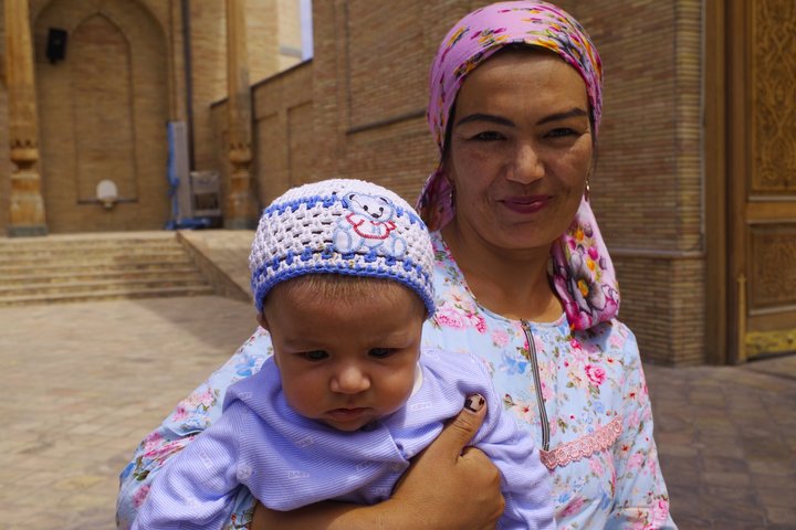Usbekin trägt ihr Kind auf dem Arm