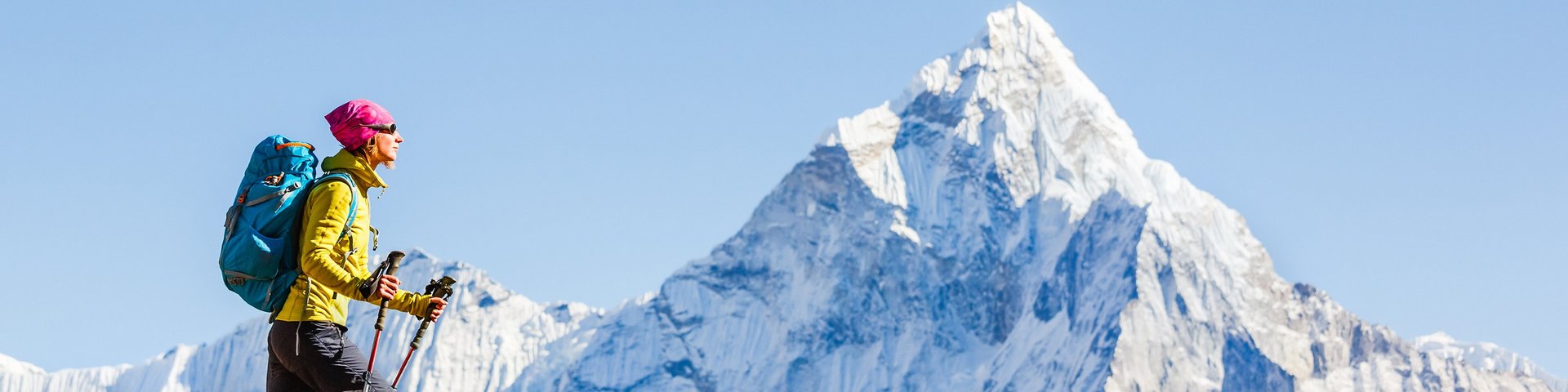 Frau wandert in Nepal, im Hintergrund ein mächtiger Berggipfel mit Schnee