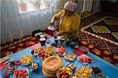 Eine Kirgisin am reichhaltig gedeckten Mittagstisch zuhause