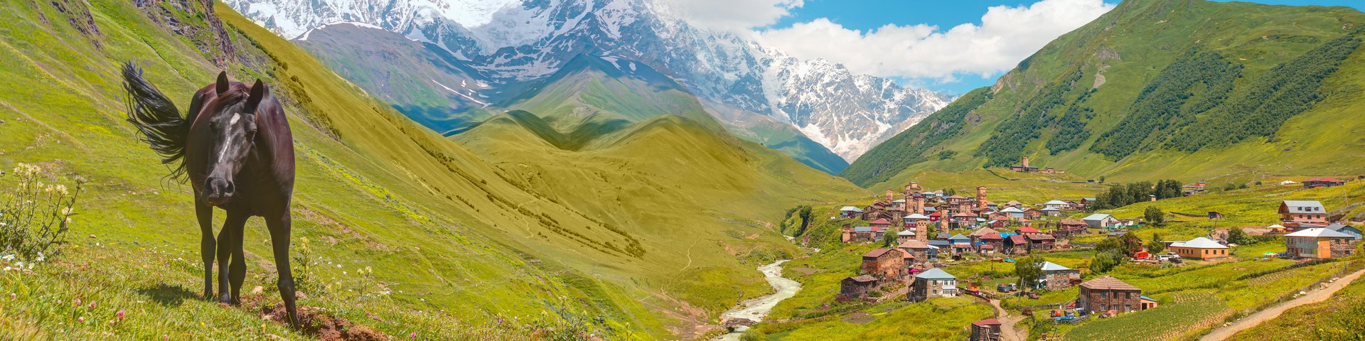 Blick aufs Bergdorf Uschguli im Kaukasus in Georgien, daneben steht ein Pferde