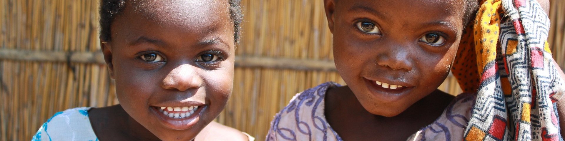 Zwei Mädchen lächeln in einem Dorf in Malawi in die Kamera