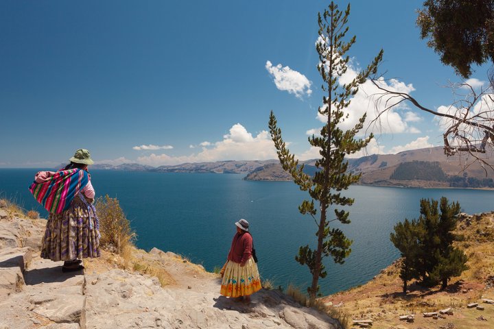 Zwei Bolivianerinnen mit traditioneller Kleidung begegnen sich oberhalb des Titicacasees