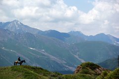 Ein einsamer Reiter auf seinem Pferd vor einer Bergkulisse in Kirgistan