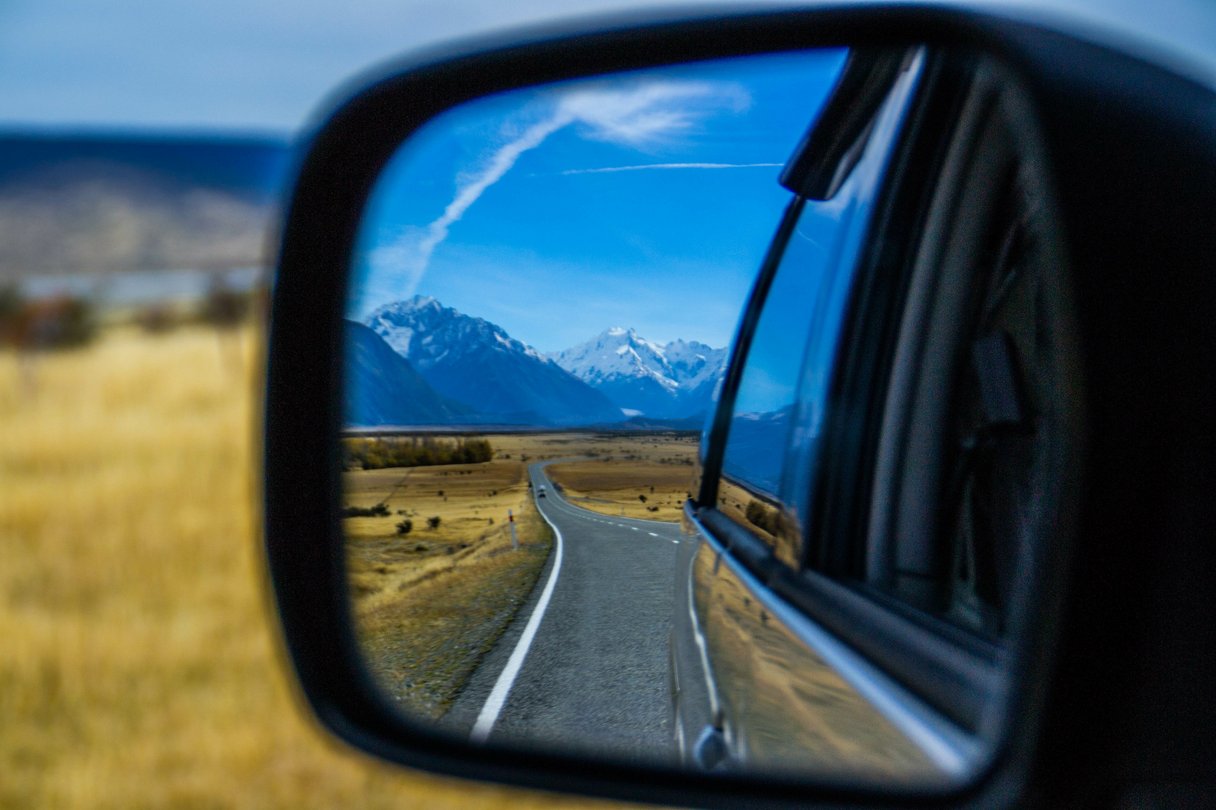 Blick durch den Rückspiegel auf die Strasse und die Berge von Neuseeland