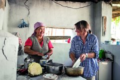 Eine Touristin hilft einer Kirgisin bei der Küchenarbeit
