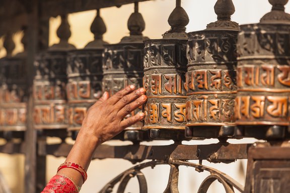 Frau dreht an Gebetsmühlen in Nepal