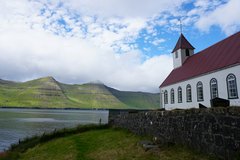 Weisse Kirche mit einem roten Dach am Meer auf den Färöer Inseln