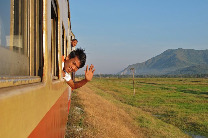 Ein Junge winkt aus einem offenen Zugfenster eines Zuges