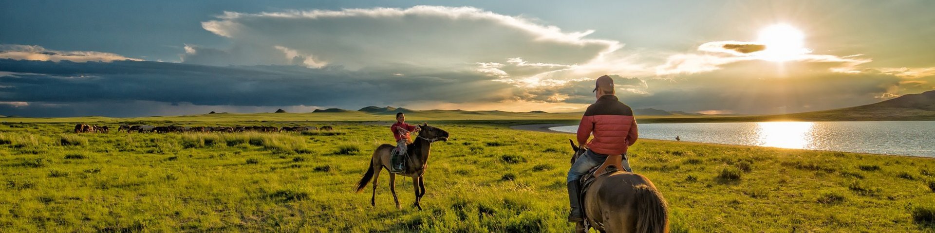 Zwei Reiter auf ihren Pferden bei Sonnenuntergang in der Mongolei