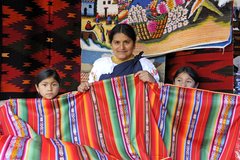 Marktfrau mit Kindern und farbigen Textilien in Otavalo