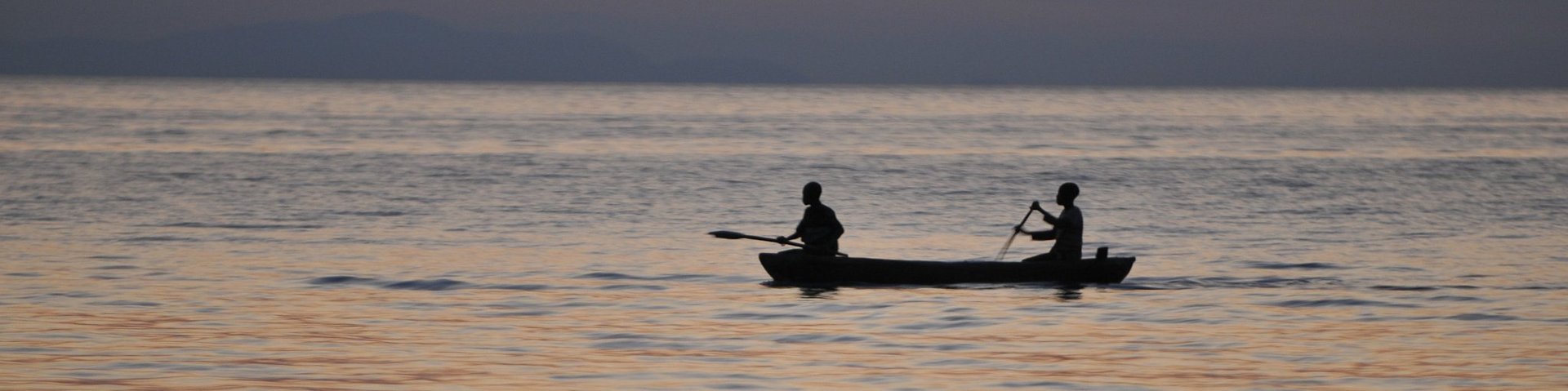 Zwei Einheimsiche rudern auf einem Boot Mitten auf dem Malawi-See