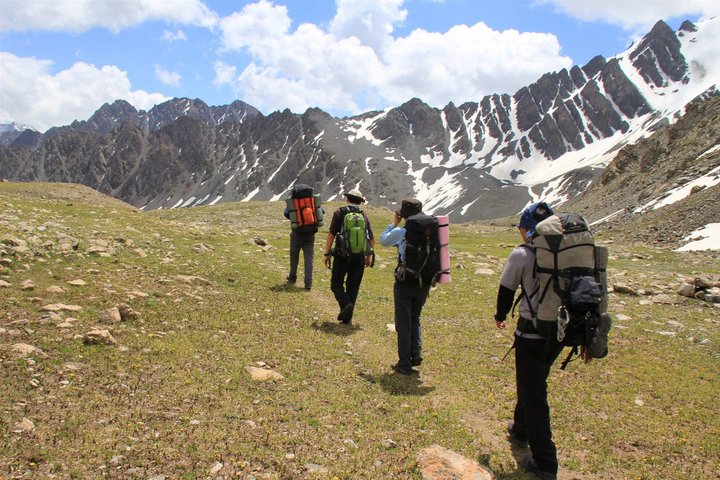 Vier Personen wandern durch die Gebirgswelt von Kirgistan