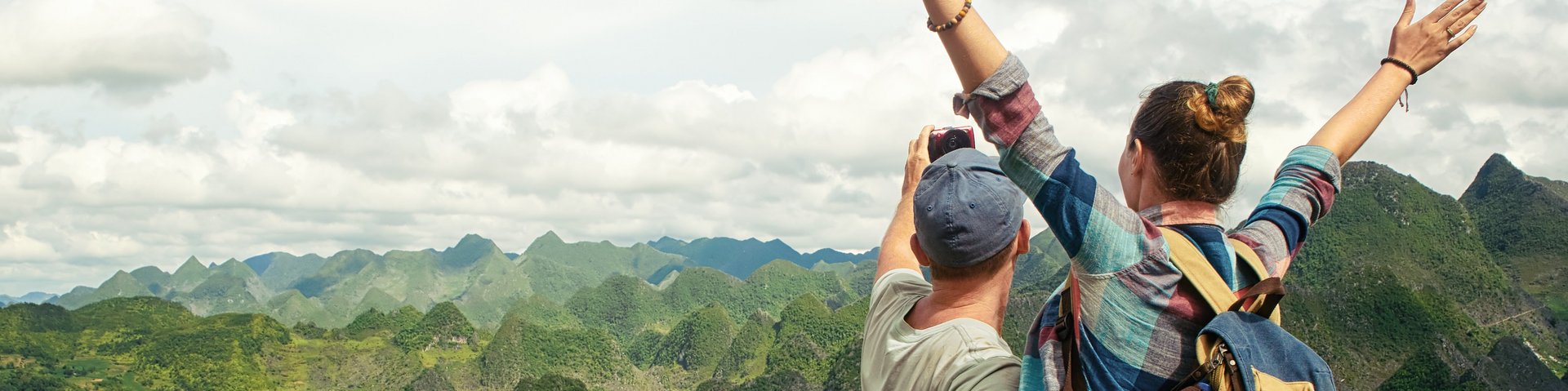Individualreisende machen Selfie vor einer grünen Hügellandschaft