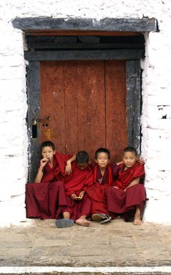 Junge Mönche sitzen vor einem Hauseingang in Bhutan
