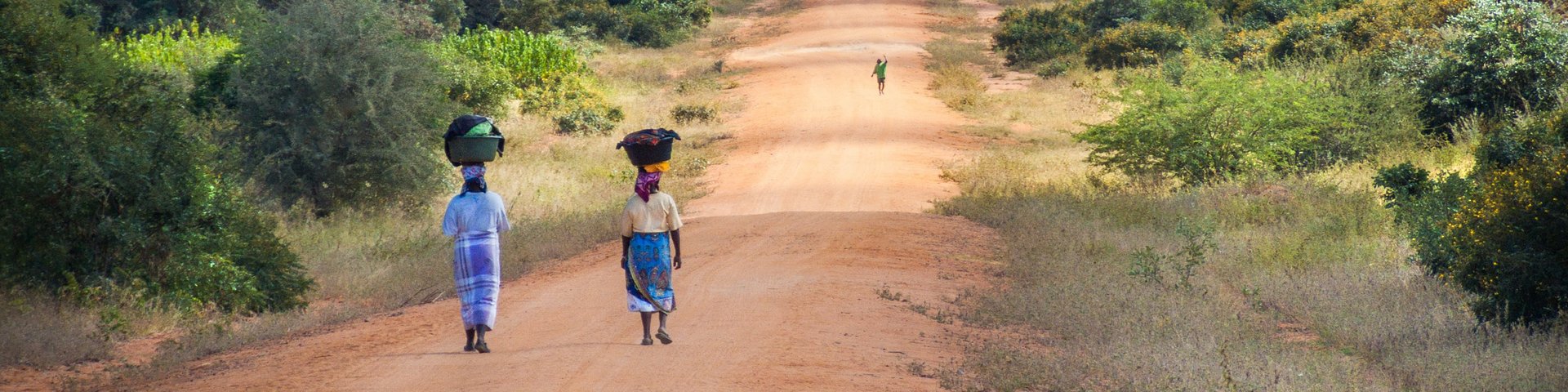 Zwei einheimische Frauen gehen auf einer Naturstrasse in Mosambik