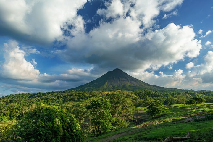 Blick über die grüne Ebene hin zum Vulkan Arenal in Costa Rica