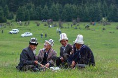 Kirgisische Nomaden sitzen zusammen im Gras