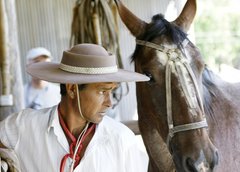 Ein Gaucho mit Hut steht neben seinem Pferd